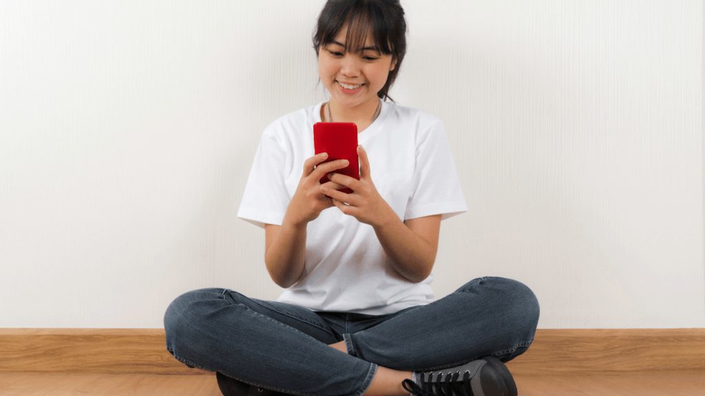 A person smiling while looking at their phone