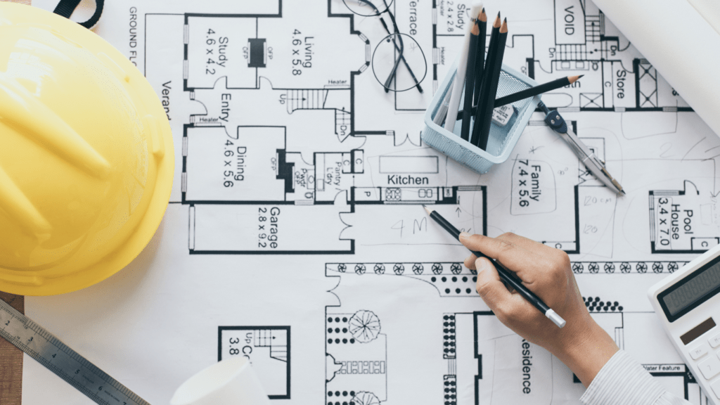 a person is working on blueprints with a hardhat and pencil