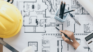a person is working on blueprints with a hardhat and pencil