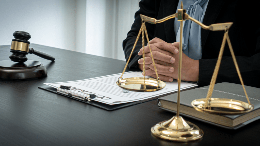 a lawyer sits at a desk with a gavel and scales of justice in front of them