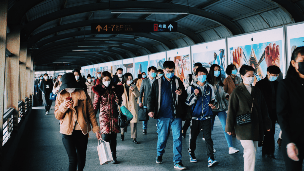 People wearing face masks walk through a subway station