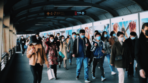 People wearing face masks walk through a subway station