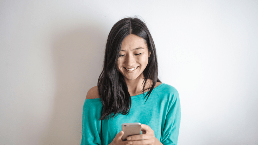 A person smiling while looking at their phone