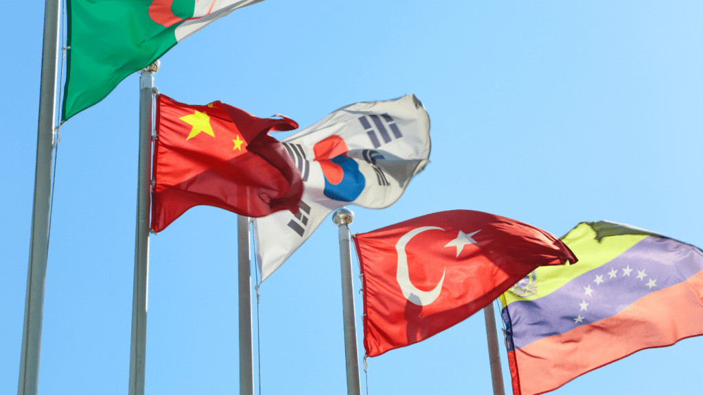 several flags of different countries flying in the wind