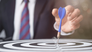 a person in a suit holding a dart in the center of a target