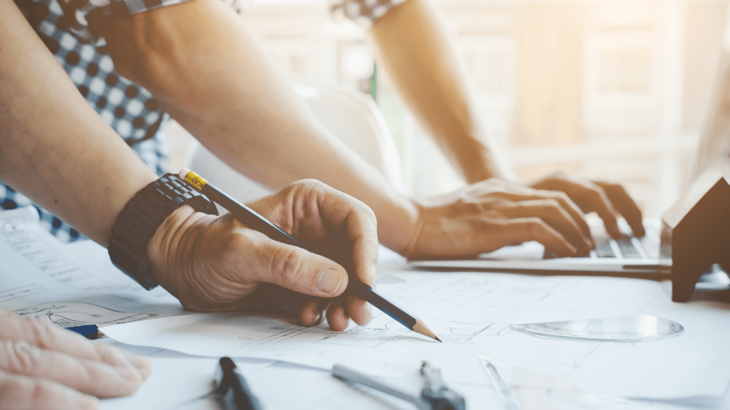 a person is working on blueprints with a hardhat and pencil