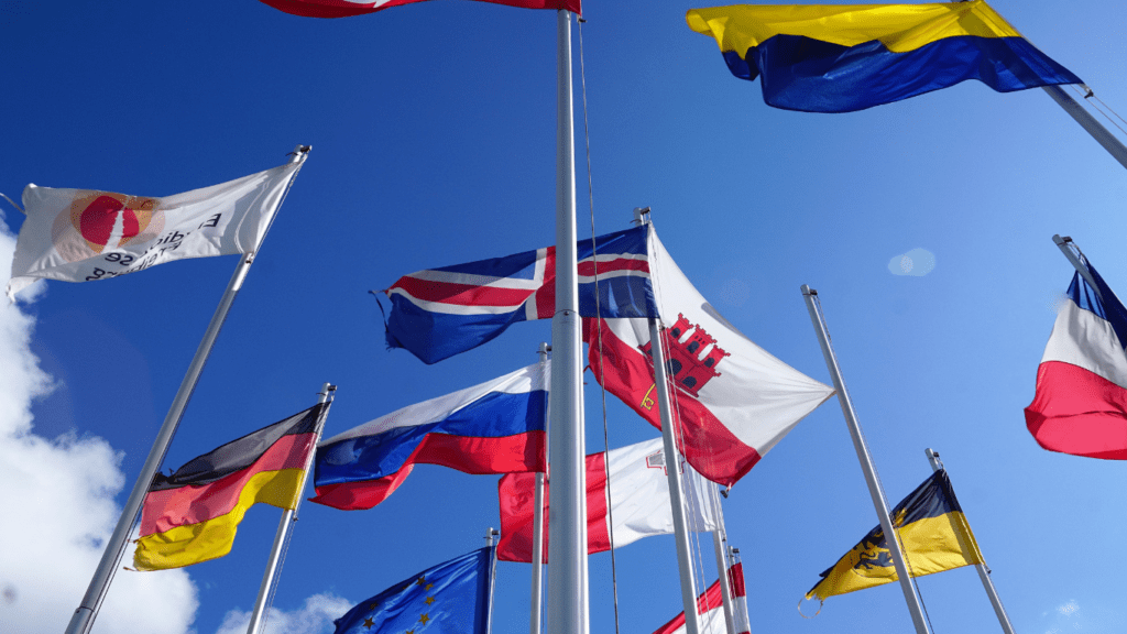 several flags of different countries flying in the wind