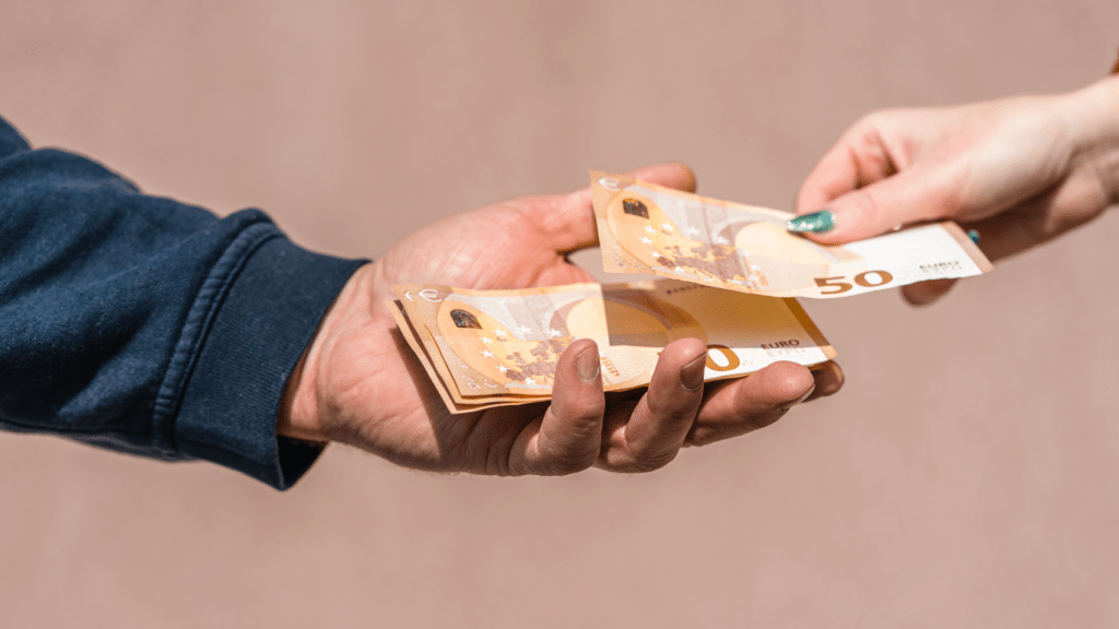 two people handing money to each other 