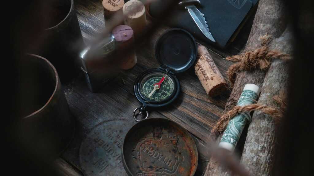 An arrangement of vintage travel items including a compass and corks on a rustic wooden surface.